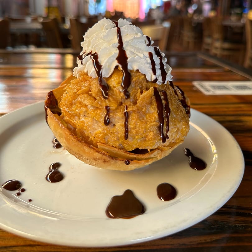 Fried ice cream dessert with whipped cream and chocolate syrup on a white plate at Hecho en Mexico.